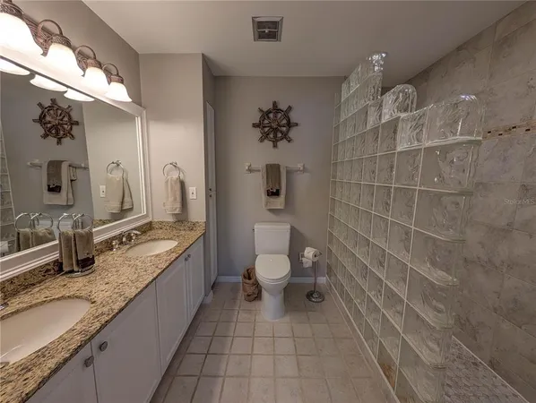 a bathroom with a granite countertop sink a toilet a mirror and shower