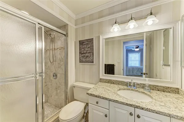 a bathroom with a granite countertop sink toilet mirror and shower