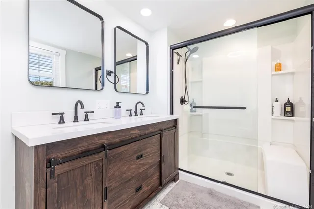 a bathroom with a double vanity sink mirror and shower