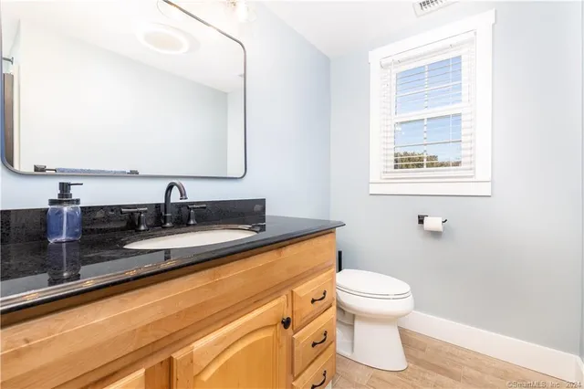a bathroom with a granite countertop sink mirror vanity and toilet