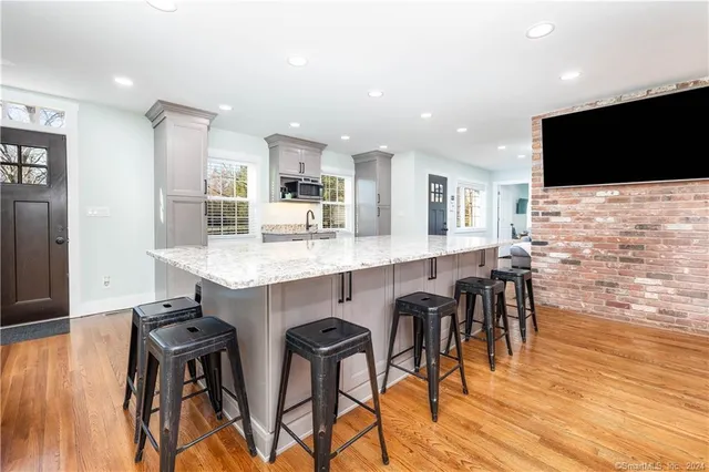 a kitchen with stainless steel appliances kitchen island granite countertop a table chairs microwave and sink