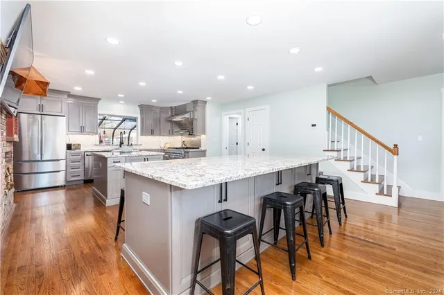 a kitchen with stainless steel appliances kitchen island granite countertop a table chairs in it and wooden floors