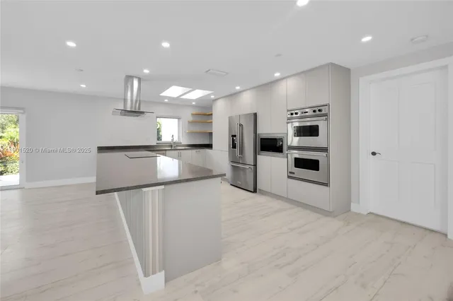 a kitchen with stainless steel appliances kitchen island granite countertop a stove and a refrigerator