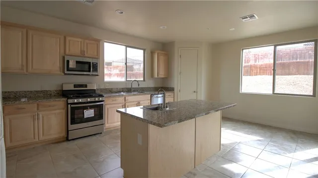 a kitchen with stainless steel appliances granite countertop a stove a sink and a microwave