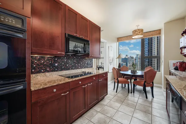 a kitchen with granite countertop a sink dishwasher a stove a microwave oven and a dining table with wooden cabinet