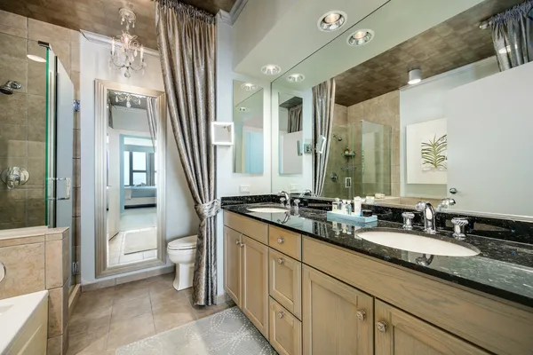 a bathroom with double vanity sinks a toilet a mirror and a glass door shower