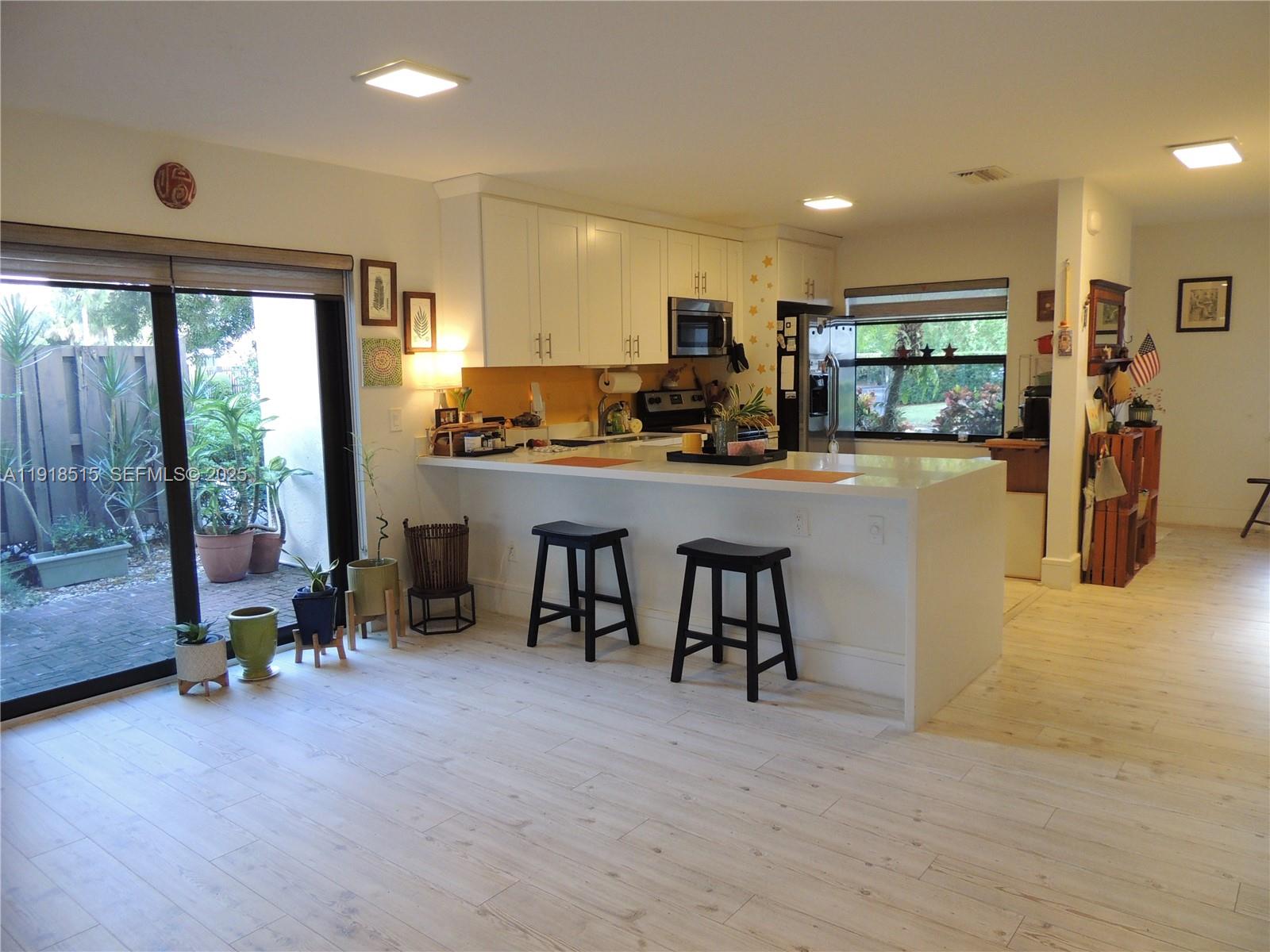 7951 Eastlake Drive, Unit C Boca Raton, FL 33433 - Photo 10 of 46 a kitchen with stainless steel appliances granite countertop a stove top oven a sink a dining table and chairs with wooden floor