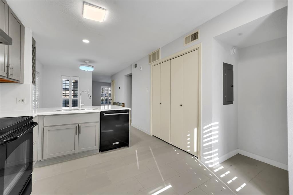 2111 East Belt Line Road, Unit 166B Richardson, TX 75081 - Photo 6 of 23 Kitchen with gray cabinetry, black appliances, a peninsula, electric panel, and light tile patterned flooring