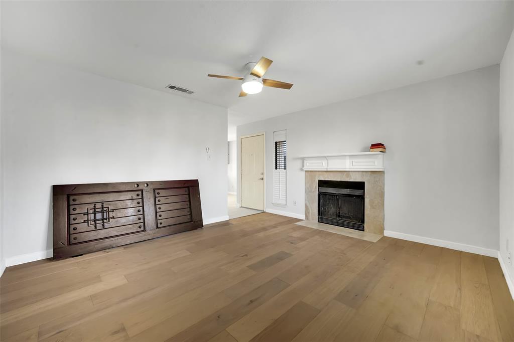 2111 East Belt Line Road, Unit 166B Richardson, TX 75081 - Photo 9 of 23 Unfurnished living room with a tiled fireplace, hardwood / wood-style floors, and a ceiling fan