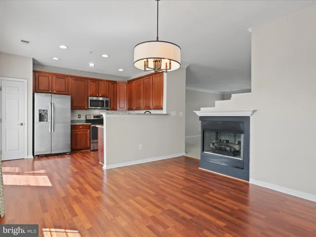 a kitchen with stainless steel appliances granite countertop a refrigerator a stove a sink and a wooden floor