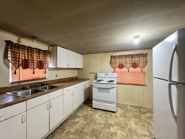 a kitchen with granite countertop a refrigerator stove top oven and sink