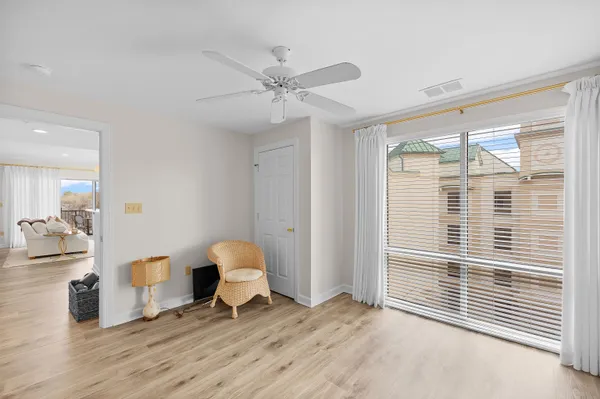 a view of empty room with wooden floor and fan