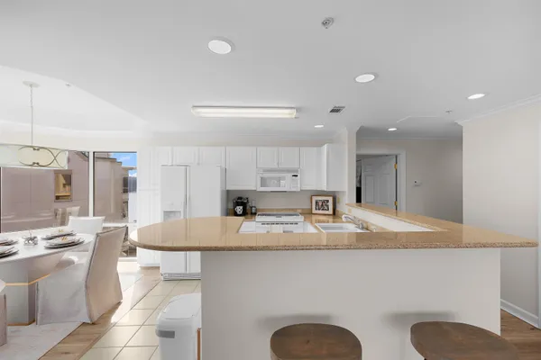 a large kitchen with kitchen island granite countertop a sink a stove a dining table and chairs
