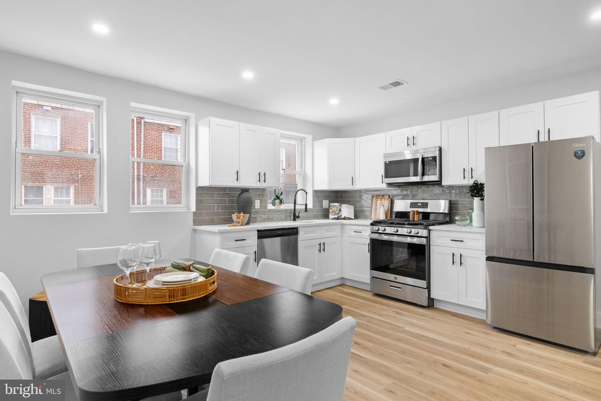 4233 Passmore Street Philadelphia, PA 19135 - Photo 8 of 30 a kitchen with stainless steel appliances granite countertop a stove a sink a refrigerator and white cabinets with wooden floor
