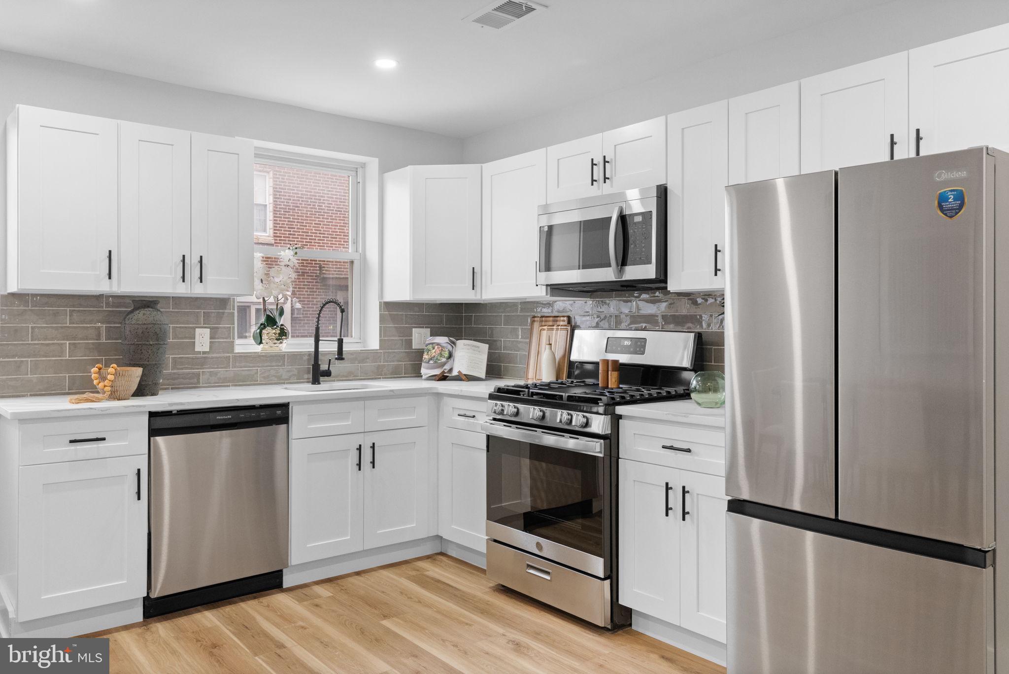 4233 Passmore Street Philadelphia, PA 19135 - Photo 9 of 30 a kitchen with stainless steel appliances white cabinets a sink a stove a refrigerator and white cabinets