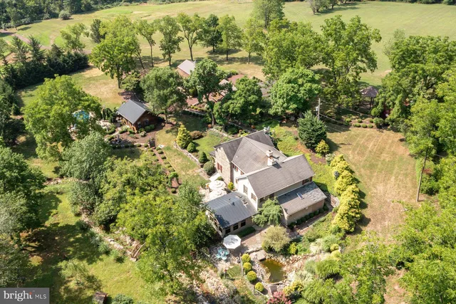 an aerial view of residential house with outdoor space and trees all around