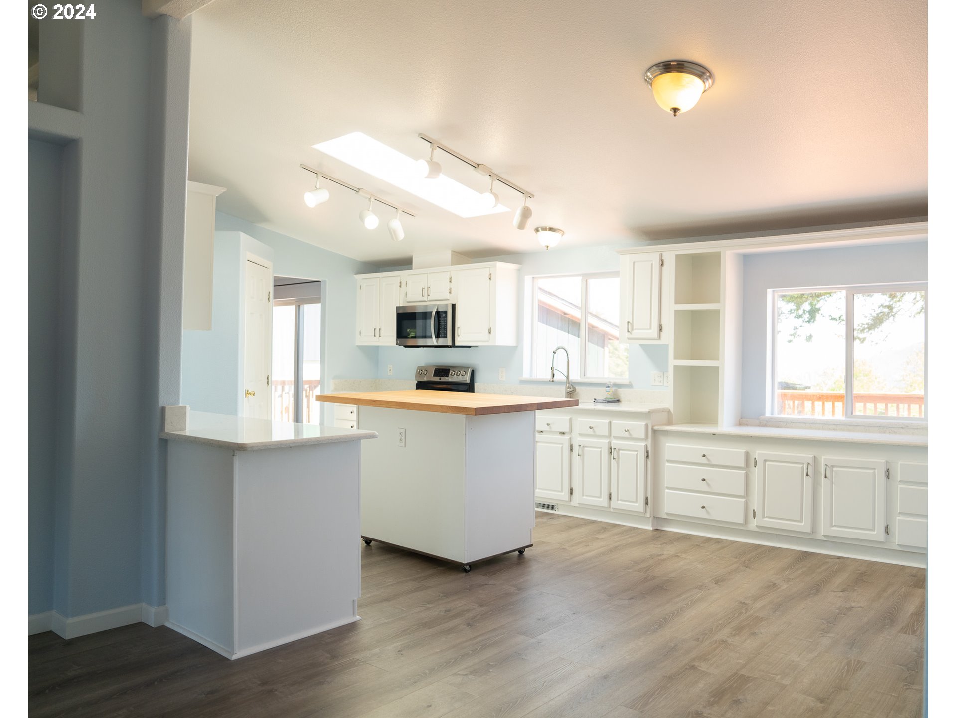 27286 Eighty Acres Road Gold Beach, OR 97444 - Photo 40 of 46 a large white kitchen with window and wooden floor