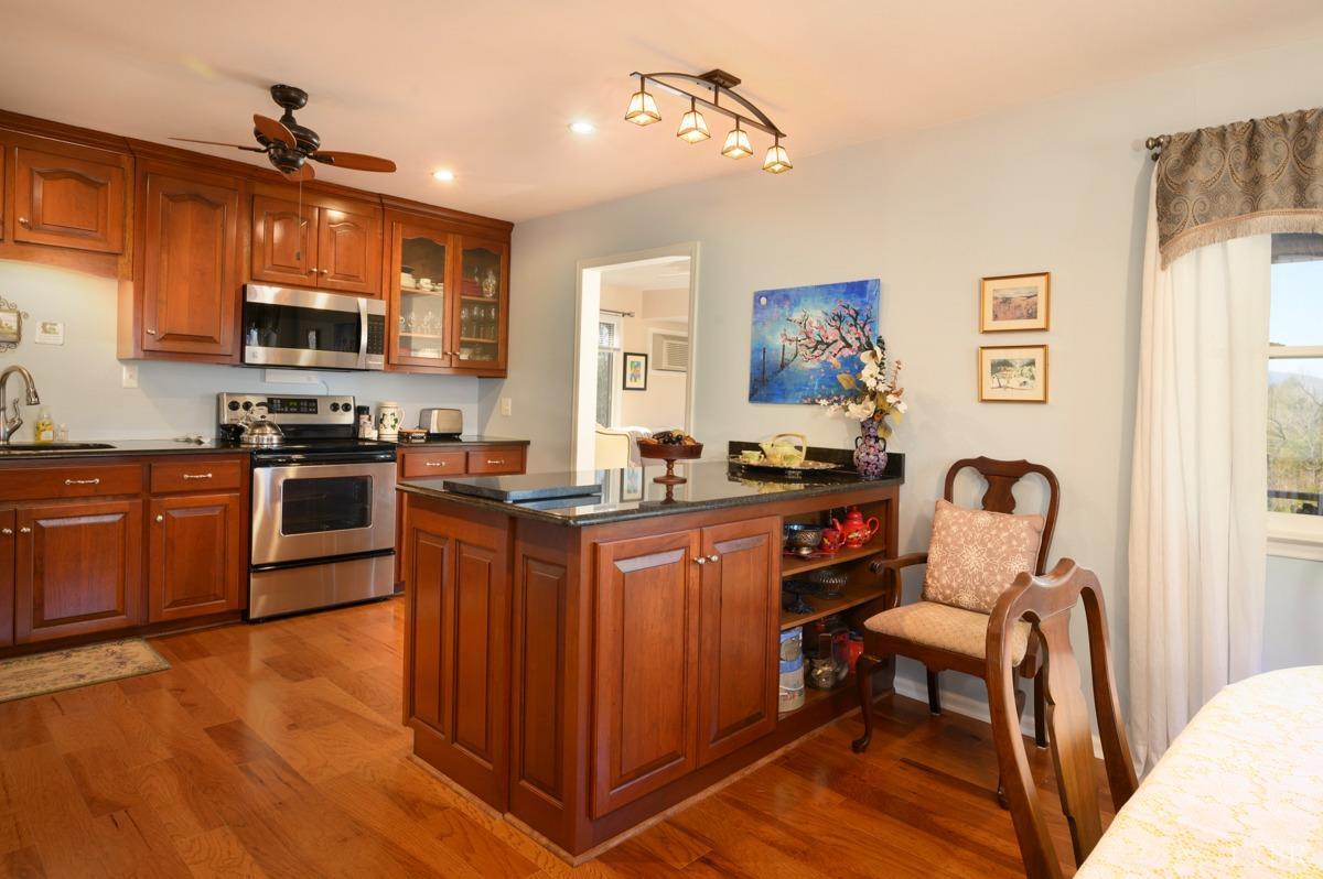 5687 Elon Road Monroe, VA 24574 - Photo 8 of 60 a kitchen with stainless steel appliances granite countertop a stove top oven a sink dishwasher a dining table and chairs with wooden floor