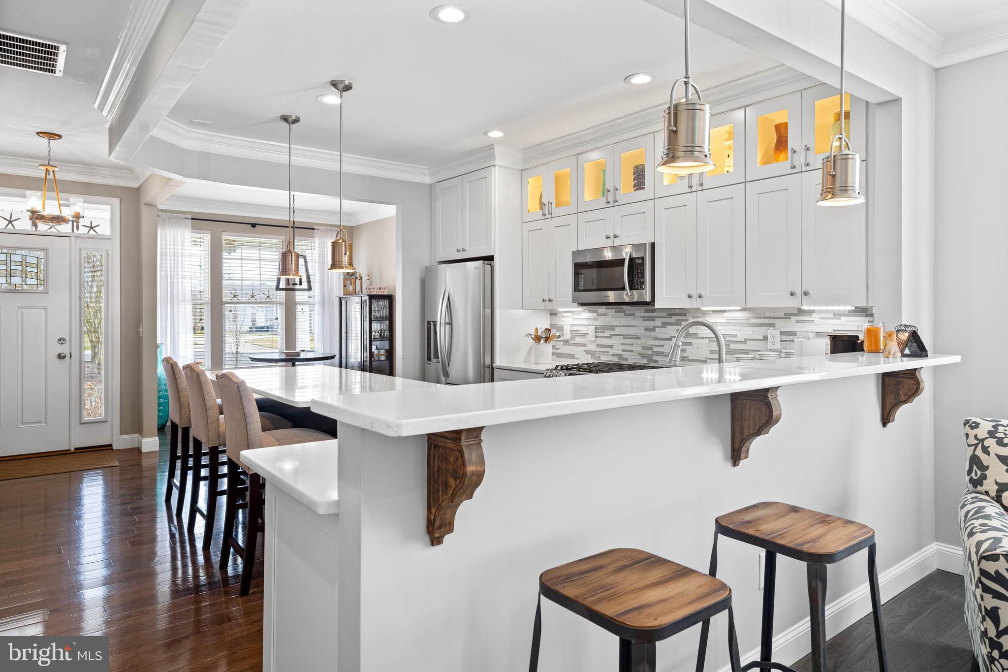 a kitchen with stainless steel appliances kitchen island granite countertop a table chairs in it and wooden floors