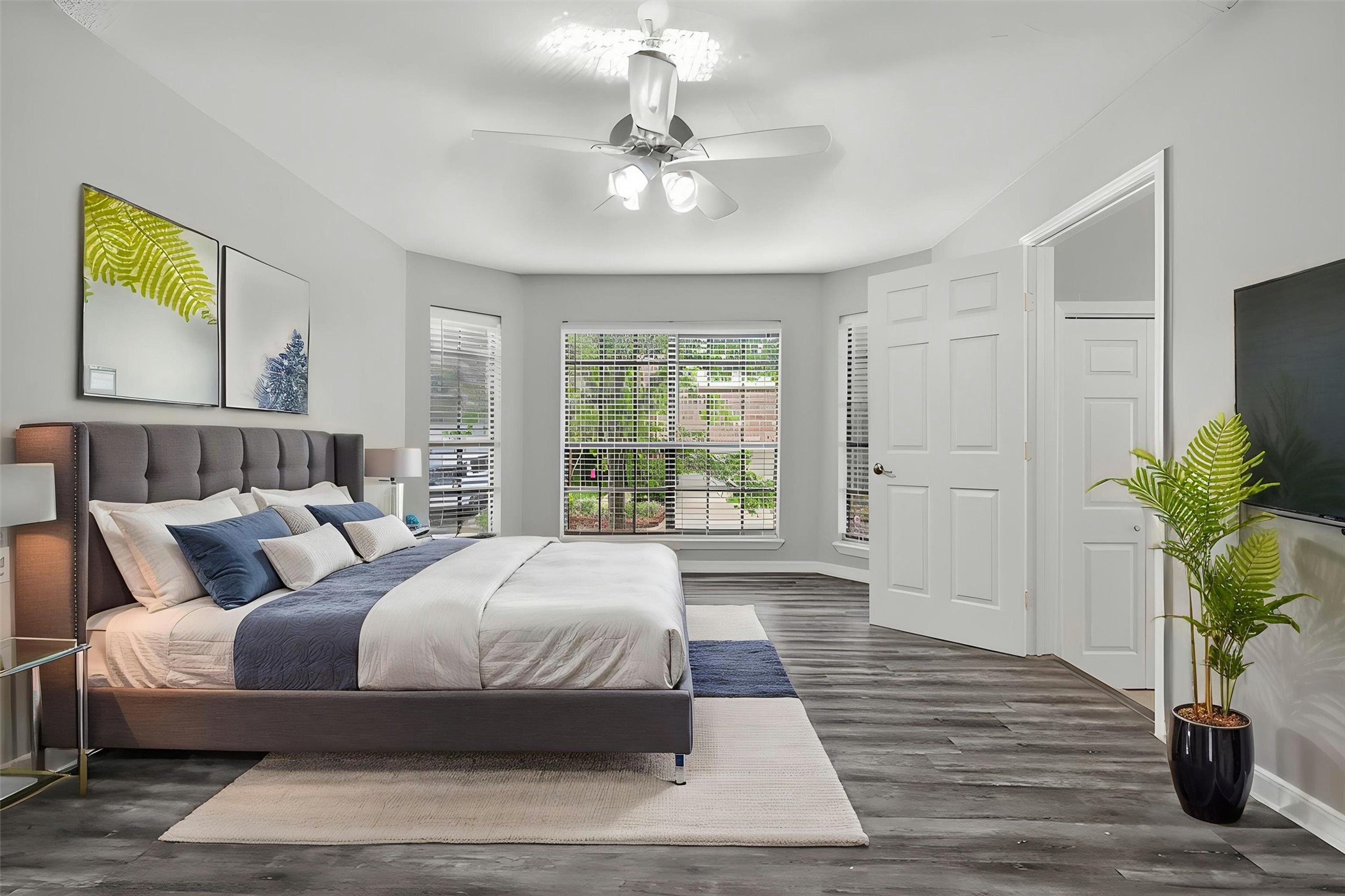 12929 Kingsbridge Lane Houston, TX 77077 - Photo 18 of 42 PrimaryVirtually Staged — Relax and unwind in this spacious primary bedroom retreat featuring oversized windows, abundant natural light, and a bright airy atmosphere buyers love. This inviting suite offers plenty of room for a king-sized setup, sitting area, or private workspace while showcasing modern flooring and neutral designer tones throughout. The expansive windows create a peaceful and elegant feel, making the space both warm and luxurious.