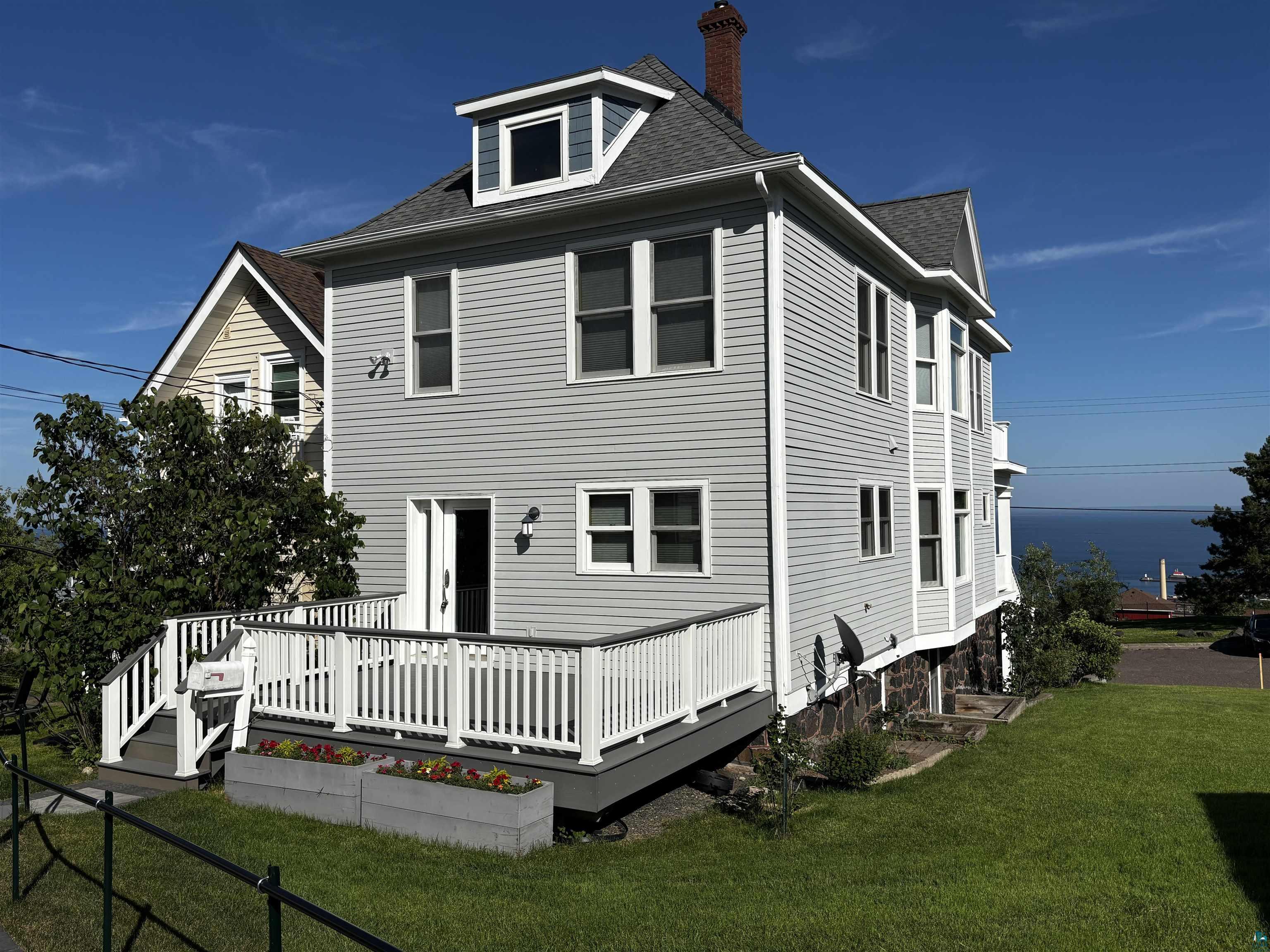 13 West 8th Street Duluth, MN 55806 - Photo 51 of 57 Multi-level property featuring light gray siding, a dark gray roof, and a prominent white deck with dark gray trim