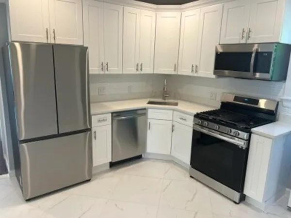 a kitchen with stainless steel appliances white cabinets white stove a microwave and a refrigerator