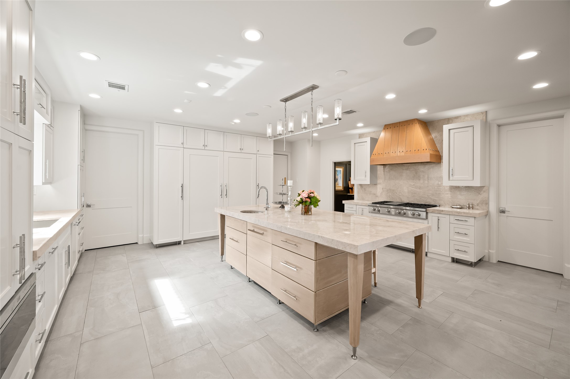 11518 Shadow Way Street Houston, TX 77024 - Photo 12 of 50 Sleek and airy, the kitchen presents Wolf appliances, an expansive island, a statement wood vent hood, and beautifully coordinated cabinetry. The blend of textures and tones creates a sophisticated culinary environment.