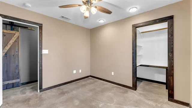 an empty room with closet and a chandelier fan
