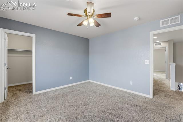 2224 Reed Grass Way Colorado Springs, CO 80915 - Photo 34 of 39 Unfurnished bedroom featuring light carpet, a walk in closet, and ceiling fan