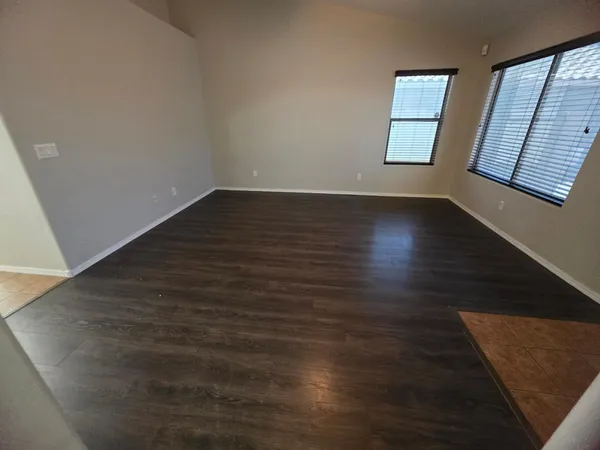 a view of an empty room with wooden floor and window