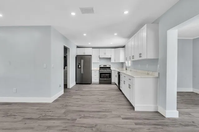 a kitchen with granite countertop white cabinets and stainless steel appliances