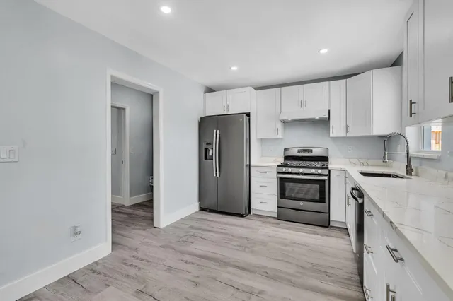 a kitchen with granite countertop white cabinets and stainless steel appliances