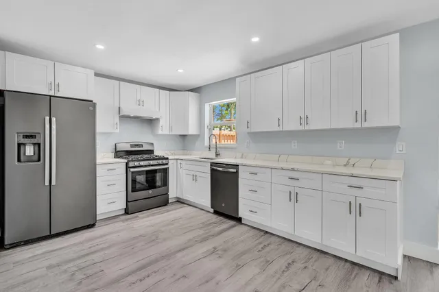 a kitchen with wooden floors white cabinets and sink