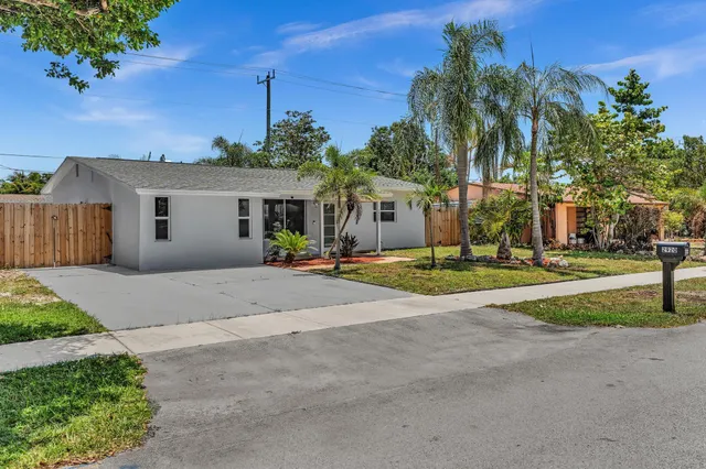 a view of a house with a small yard and palm trees