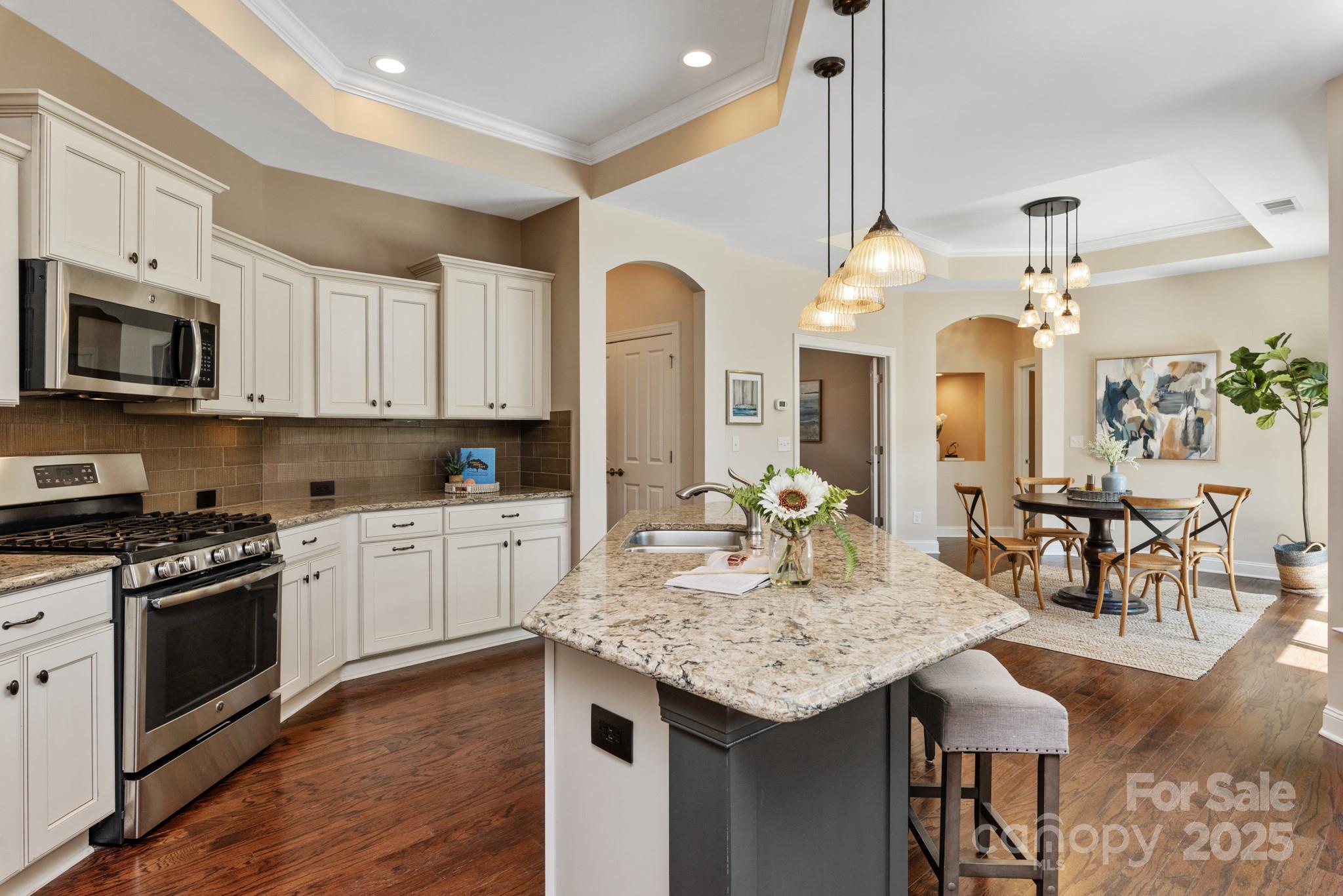 1128 Avalon Place Matthews, NC 28104 - Photo 9 of 39 a kitchen with granite countertop kitchen island stainless steel appliances a stove sink microwave and cabinets