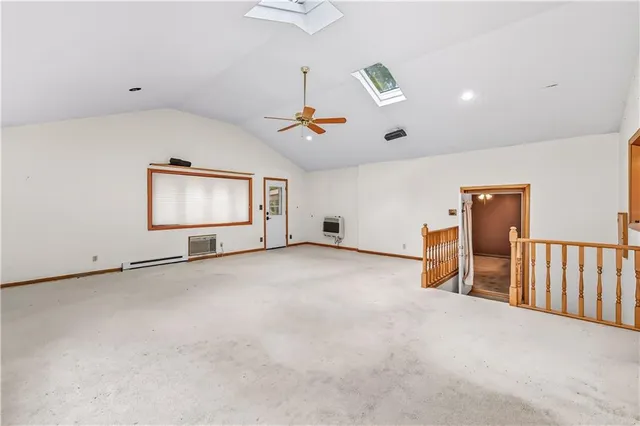 an empty room with chandelier fan and windows