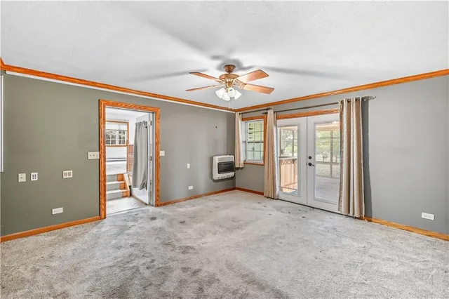 an empty room with chandelier fan and windows