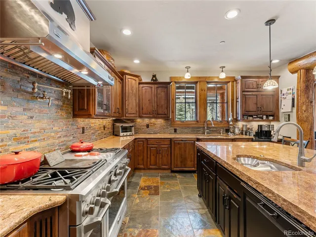 a kitchen with kitchen island granite countertop a stove and a sink