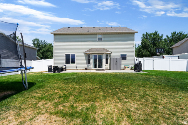 1393 West 150 North Springville, UT 84663 - Photo 21 of 31 Spacious backyard featuring a large concrete patio, double sliding glass doors, multiple windows, and a white privacy fence