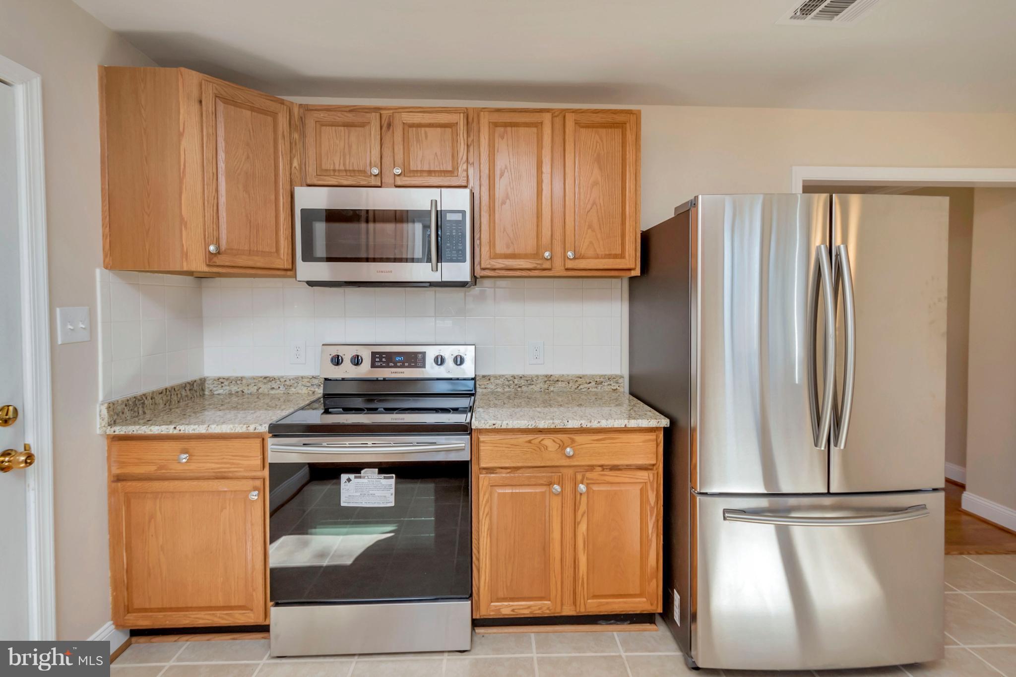 14114 Grayson Road Woodbridge, VA 22191 - Photo 10 of 28 a kitchen with stainless steel appliances granite countertop a refrigerator stove and microwave
