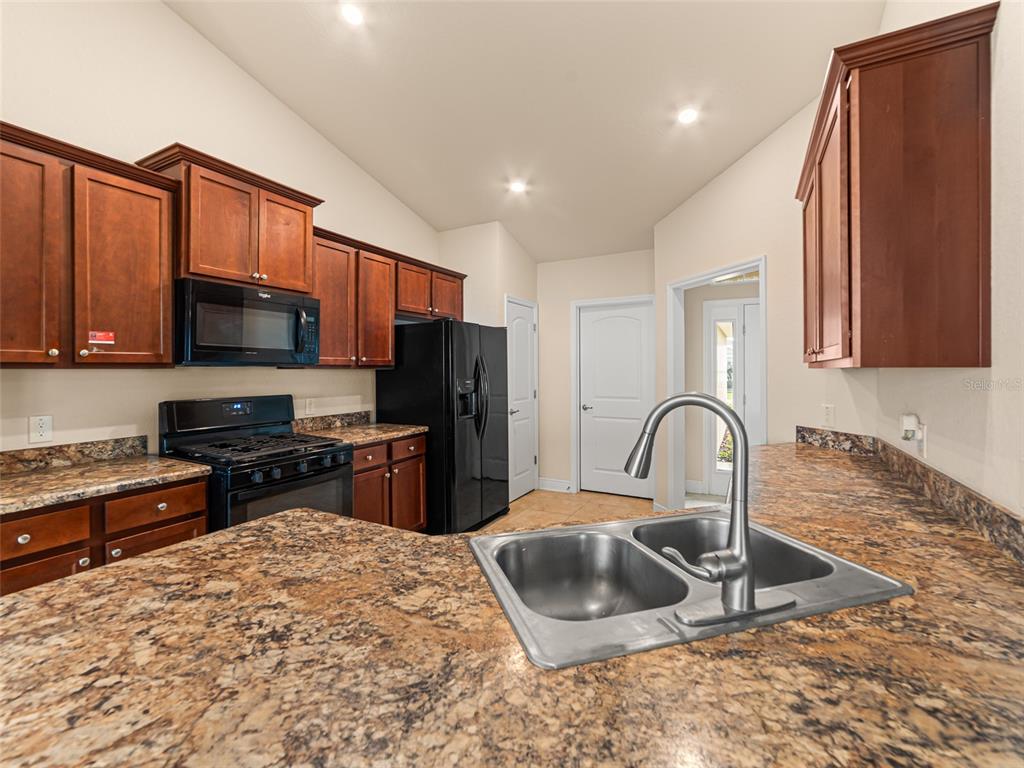 2412 Twin Lake View Road Winter Haven, FL 33881 - Photo 8 of 26 a kitchen with stainless steel appliances granite countertop a sink a stove a refrigerator cabinets and a stove top oven