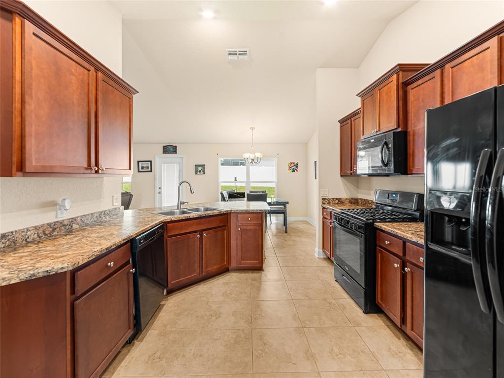 2412 Twin Lake View Road Winter Haven, FL 33881 - Photo 10 of 26 a large kitchen with stainless steel appliances granite countertop a stove top oven a sink dishwasher a refrigerator and a microwave