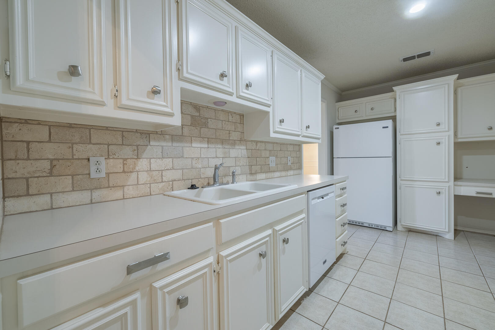 5415 68th Street Lubbock, TX 79424 - Photo 38 of 57 a kitchen with white cabinets and white appliances