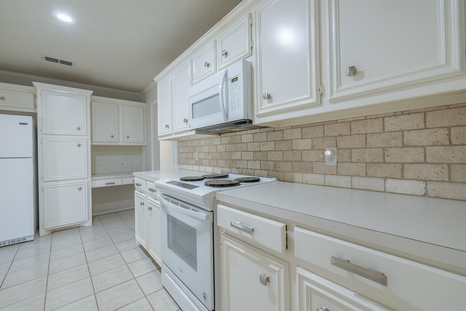 5415 68th Street Lubbock, TX 79424 - Photo 39 of 57 a kitchen with white cabinets and white appliances