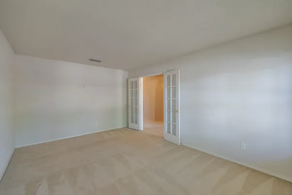 an empty room with a window and a chandelier fan