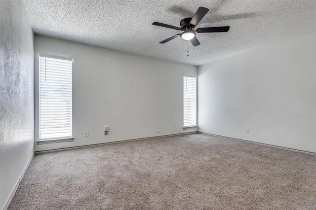 an empty room with windows and ceiling fan