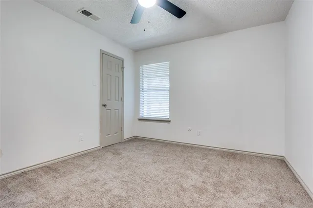 an empty room with a ceiling fan and window