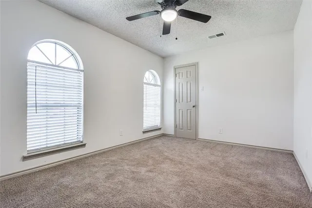 an empty room with a window and a fan