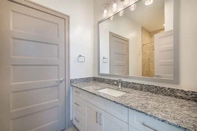 a bathroom with a granite countertop sink and a mirror
