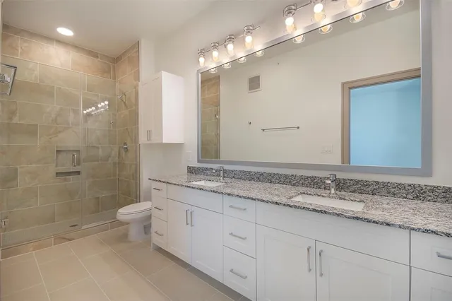 a bathroom with a granite countertop sink a toilet and shower